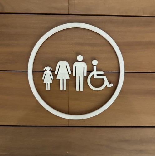 Une porte en bois avec un cercle incluant une enfant, une femme dont le cercle représentant la tête est manquant ainsi qu’un homme et une personne en chaise roulante