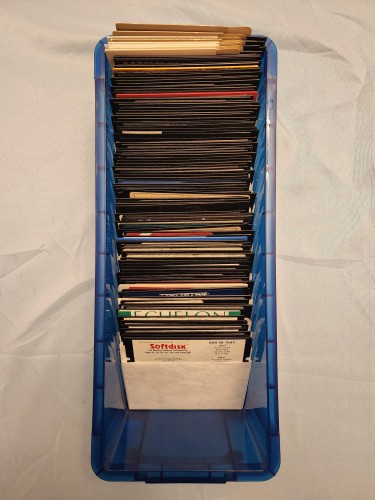 A blue plastic container with a large stack of 5.25 inch floppies inside 