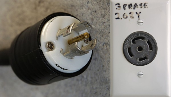 A twist lock plug: it has a central ground pole, and 4 prongs around it in a circle, one of which has a keyed "L" bend to make sure it's inserted properly. Next to it is the matching socket: a central hole and 4 slots around it in a circle, one of which is keyed. 