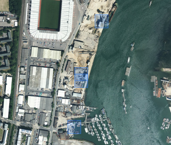 A satellite photo of a port in Southampton, UK. Blue boxes indicating search query results for "crane" surround a series of cranes.