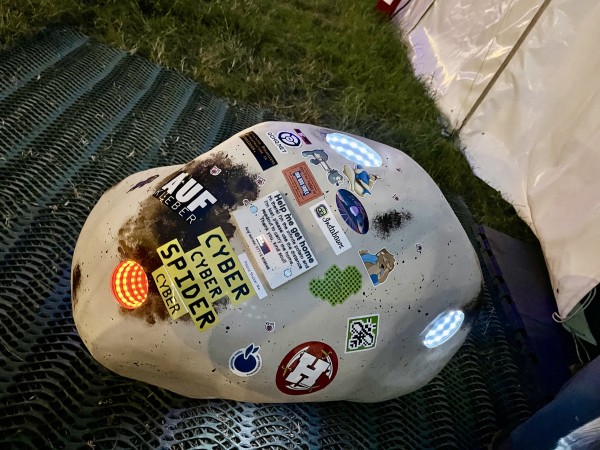 A large, potato-shaped white blob covered in stickers and with a number of illuminated holes. The holes contain rings of LEDs.