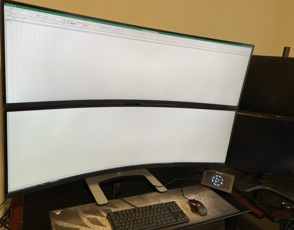 Two massive curved monitors filled with a spreadsheet.