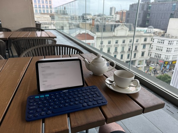 Rooftop cafe overlooking London’s Oxford Street. iPad mini and keyboard are on the table next to a teapot and mug. 