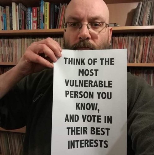 Pic of a man holding a poster that says "Think of the most vulnerable person you know, and vote in their best interests".
