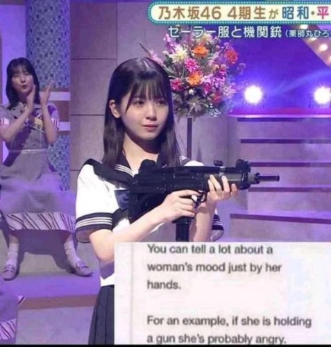 Still image. Screenshot of what appears to be a TV show. Person with long hair and bangs holding a machine pistol with another person seated in the background, mid-clap. 

Insert reads:

You can tell a lot about a 
woman's mood just by her
hands.

For an example, if she is holding
a gun she's probably angry. 