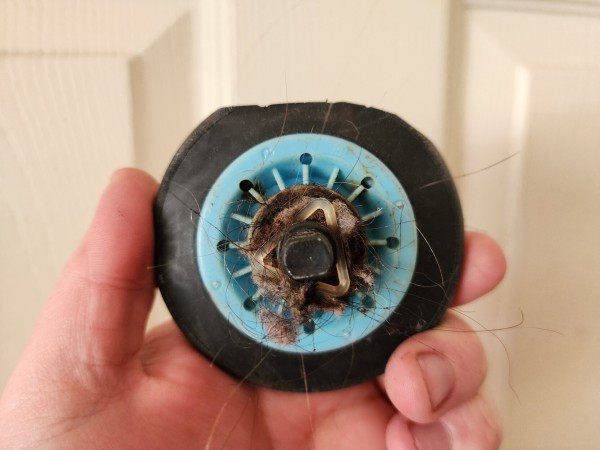 A rubber dryer wheel. A significant amount of material has been rubbed off one side, making it flat rather than curved. 