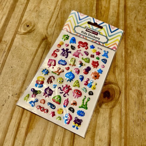 A pack of kids foam stickers with weird animals and aliens lying on a wooden table.