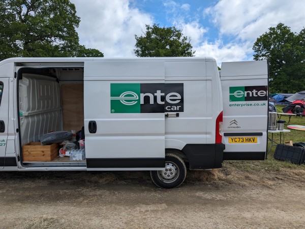 The back of a rental van parked on a muddy road. The side door is open and the company logo is shortened to "ente", which is German for duck. The same is visible on the back door.