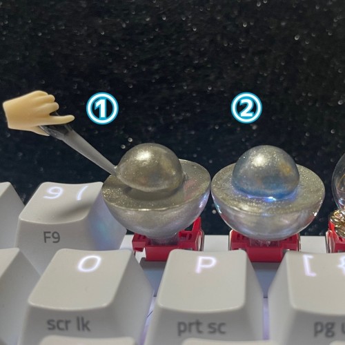 Still image. Two keycaps, side by side, labeled 1 and 2. 
1: large hemisphere with a smaller hemisphere above it, separated by a tool (canonically a screw driver) and a disembodied hand. 
2: same hemispheres, except the hand and tool are gone, the hemispheres have clapped like the cheeks of doom, and there is a pale blue glow from within. 