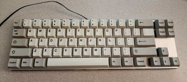 A small mechanical keyboard with grey/beige keycaps.

There's no F-keys, and the insert-cluster has only insert/delete/pageup/pagedown. the insert-cluster and arrow keys are slightly offset from the rest. 