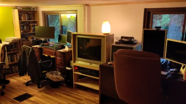 A CRT TV in a homemade hutch in a nice room with a wooden floor and one green wall