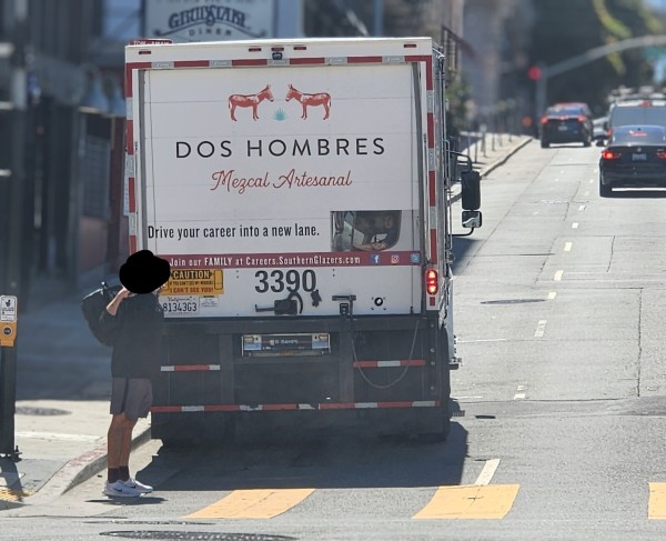 A truck parked on a San Francisco road. The back of the truck says it's for "DOS HOMBRES", a brand of mezcal