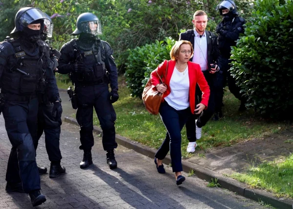 Eine Faschistin auf der Flucht in Polizeigeleit. Sie trägt die typischen Farben des dritten Reichs: Rot Weiß Schwarz