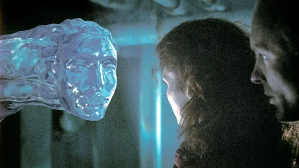 Two people looking at a watery sausage with a face on the end, from the film The Abyss