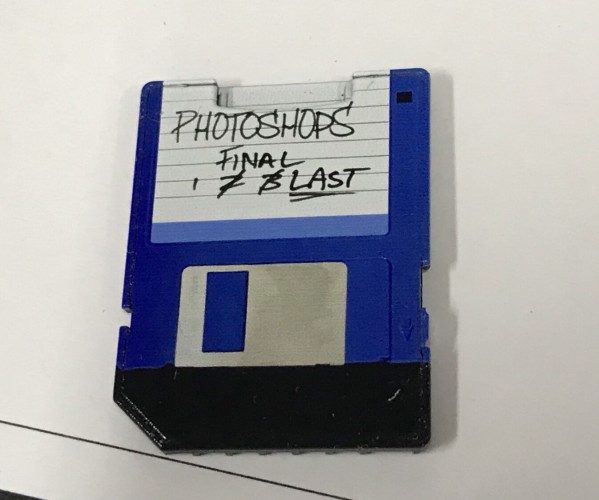 A photo of an sd to micro sd card adaptor with a 3.5 inch floppy disk printed on it. 