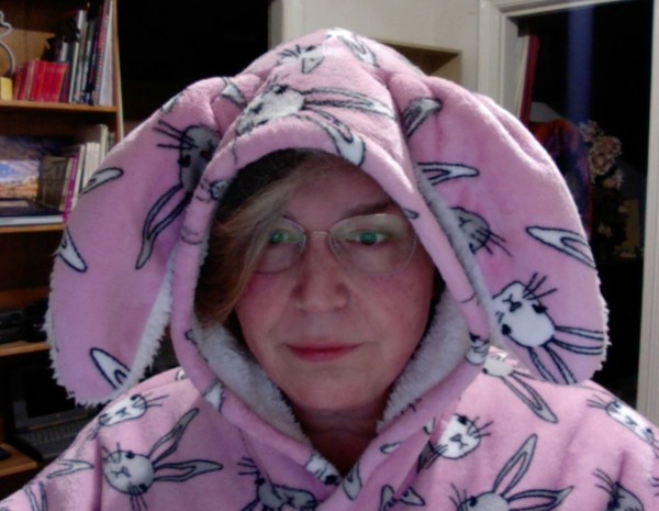 Only the third most ridiculous photo of me, a white woman wearing glasses lit by a computer screen and wearing a giant pink bunny hoodie with floppy ears.