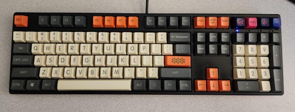 A full-profile keyboard. The letters and numbers are beige, the modifiers are black, and special keys like arrows and printscreen/scroll lock/pause/etc are orange. 
There's also an extra 4 keys above the numpad, which are labeled with a spacey logo, PANIC, a meteor, and ANY 